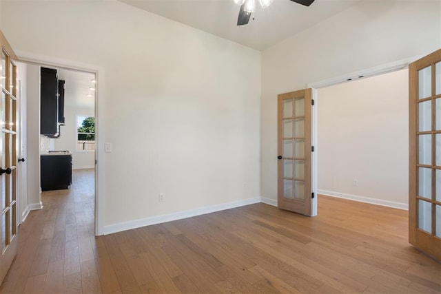 unfurnished room featuring french doors, light wood-type flooring, and ceiling fan