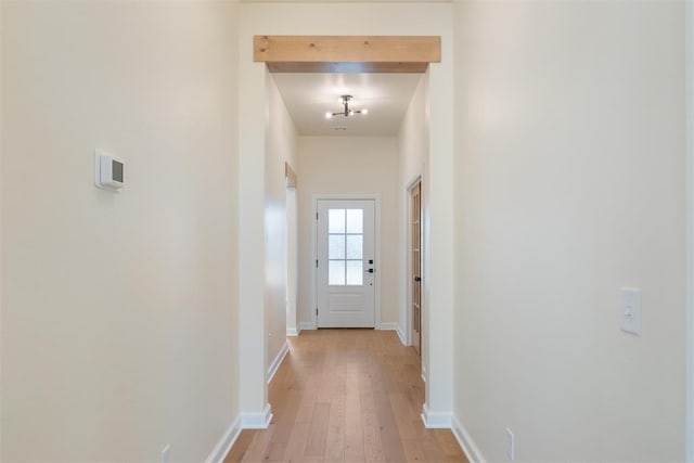 corridor with beam ceiling and light wood-type flooring