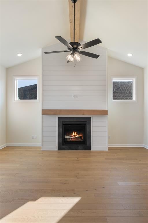 unfurnished living room featuring ceiling fan, a fireplace, vaulted ceiling, and light wood-type flooring