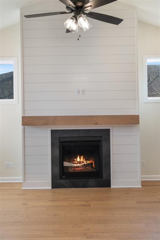 details featuring ceiling fan, a large fireplace, wood-type flooring, and wooden walls