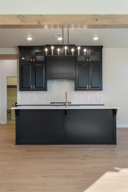 kitchen with pendant lighting, tasteful backsplash, light hardwood / wood-style floors, and sink