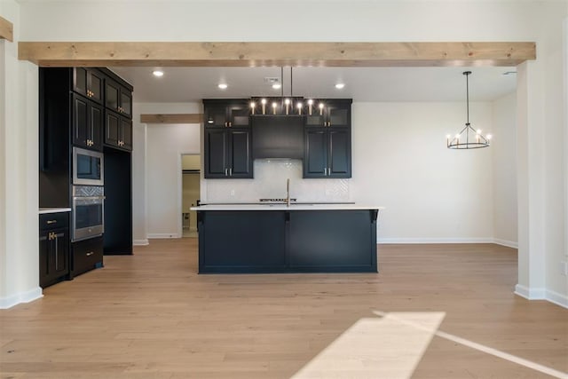 1103 Mount Irving Way, Norman, OK 73071 - kitchen with appliances with stainless steel finishes, light wood finished floors, a chandelier, decorative backsplash, and baseboards