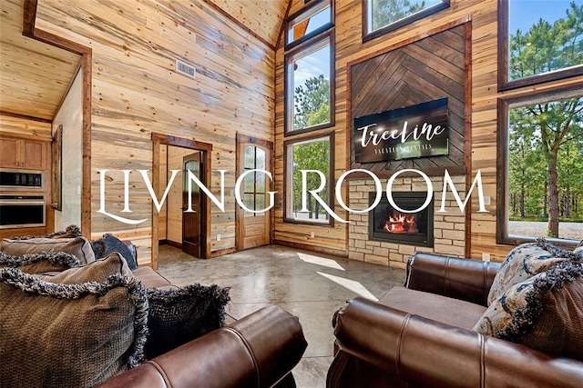 interior space with high vaulted ceiling, wooden walls, and a stone fireplace