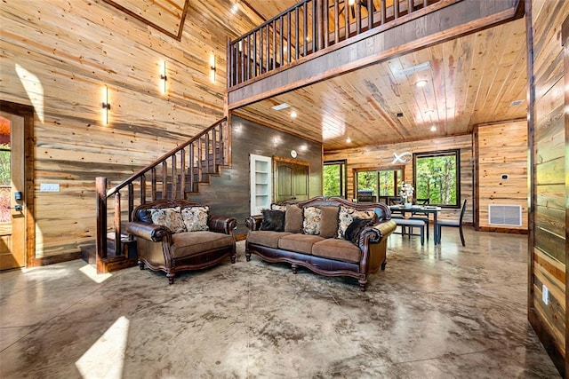 living room featuring wood ceiling, a high ceiling, wooden walls, and concrete flooring