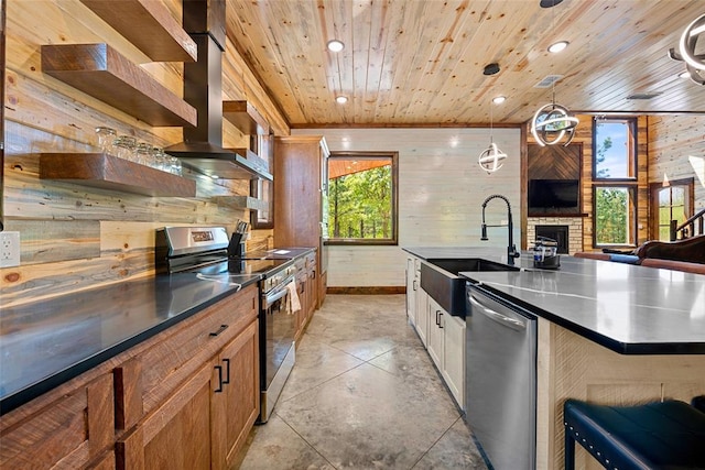 kitchen featuring sink, stainless steel appliances, wooden ceiling, decorative light fixtures, and wooden walls