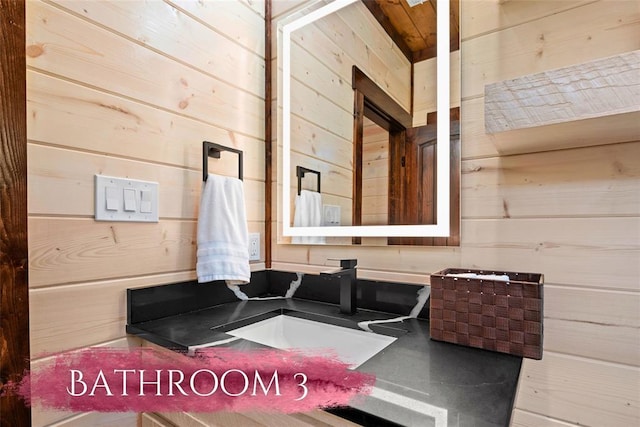 bathroom featuring wooden walls and sink