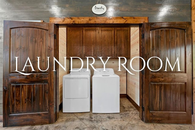 clothes washing area with washer and clothes dryer and wood walls