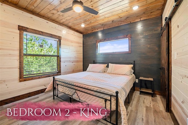 bedroom featuring wood walls, ceiling fan, a barn door, wood-type flooring, and wood ceiling