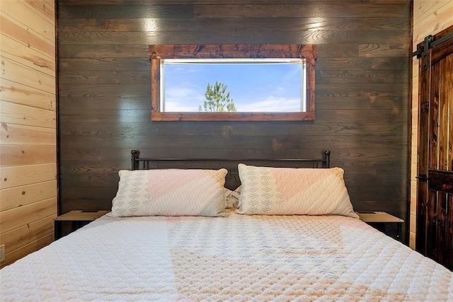 bedroom with a barn door and wood walls