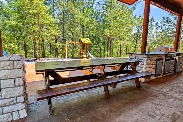 view of patio / terrace with sink, a playground, a grill, and exterior kitchen