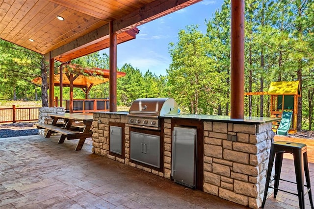 view of patio / terrace featuring area for grilling, an outdoor bar, and an outdoor kitchen