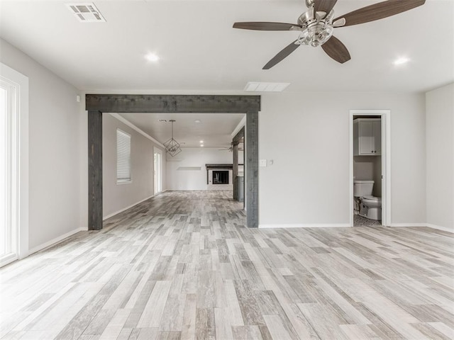 unfurnished living room featuring ceiling fan, light wood-type flooring, and a fireplace