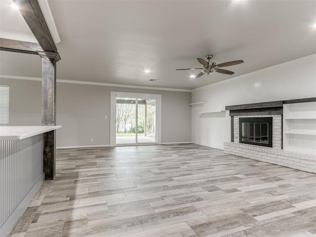 unfurnished living room featuring ceiling fan, light wood-type flooring, a fireplace, and ornamental molding