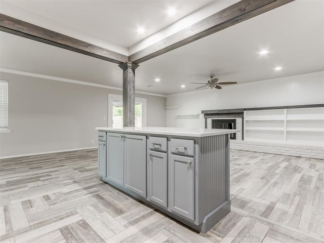 kitchen featuring decorative columns, light hardwood / wood-style floors, gray cabinets, a kitchen island, and ornamental molding