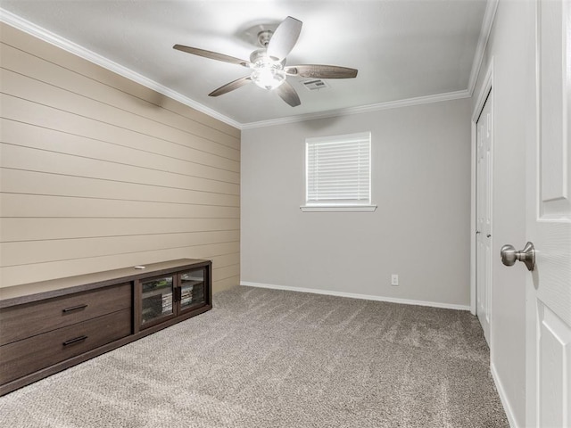 unfurnished bedroom featuring ceiling fan, crown molding, and carpet floors