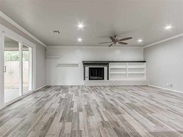 unfurnished living room with a brick fireplace, ceiling fan, ornamental molding, and light wood-type flooring