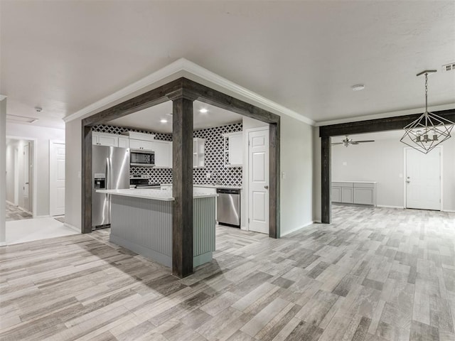 kitchen featuring white cabinetry, pendant lighting, stainless steel appliances, and light wood-type flooring