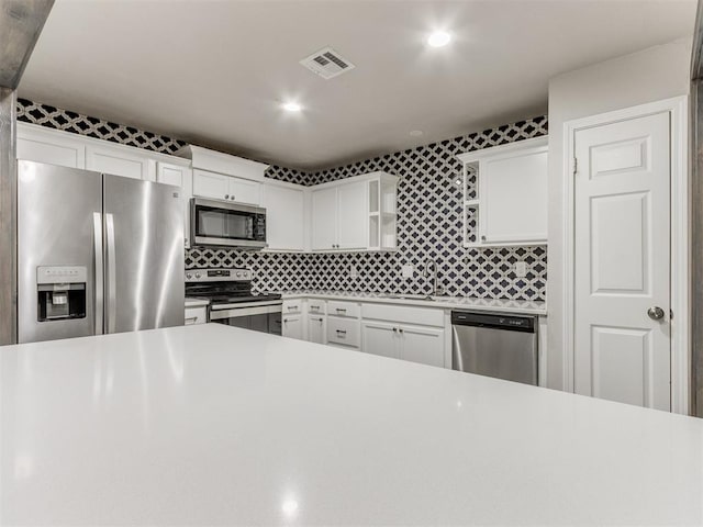 kitchen featuring decorative backsplash, appliances with stainless steel finishes, and white cabinetry