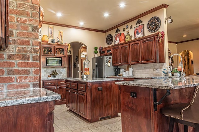 12600 SW 58th St, Mustang, OK 73064 - kitchen featuring kitchen peninsula, stainless steel fridge, backsplash, and light stone counters