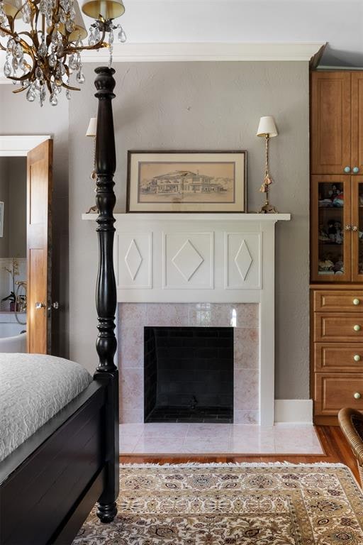 bedroom with a fireplace, wood-type flooring, and an inviting chandelier