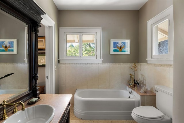 bathroom with vanity, tile walls, tile patterned flooring, toilet, and a tub