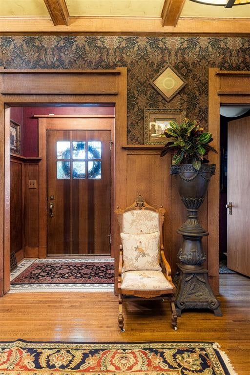 entryway with beamed ceiling, hardwood / wood-style floors, and wooden walls