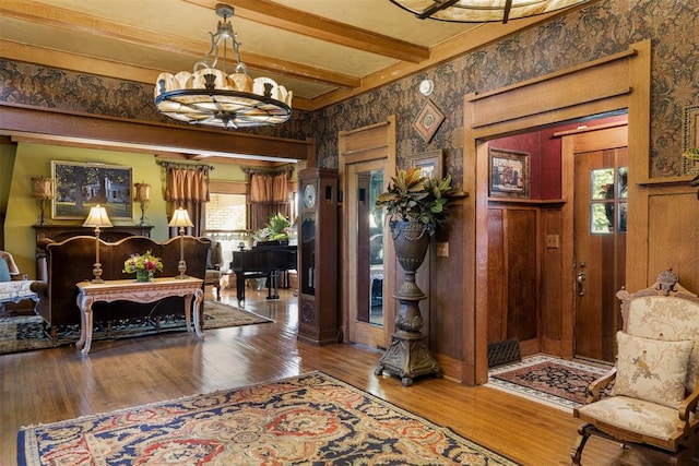 foyer entrance with beam ceiling, hardwood / wood-style flooring, and a notable chandelier