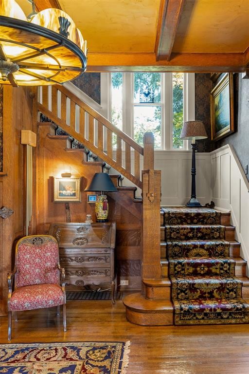 stairs featuring beamed ceiling and hardwood / wood-style flooring