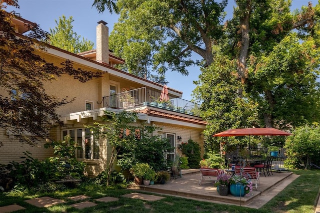 rear view of property featuring a balcony and a patio