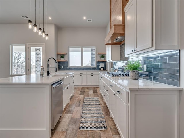 kitchen with stainless steel appliances, white cabinetry, and a kitchen island with sink