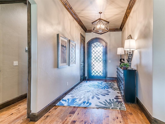 foyer with a chandelier, hardwood / wood-style flooring, and ornamental molding