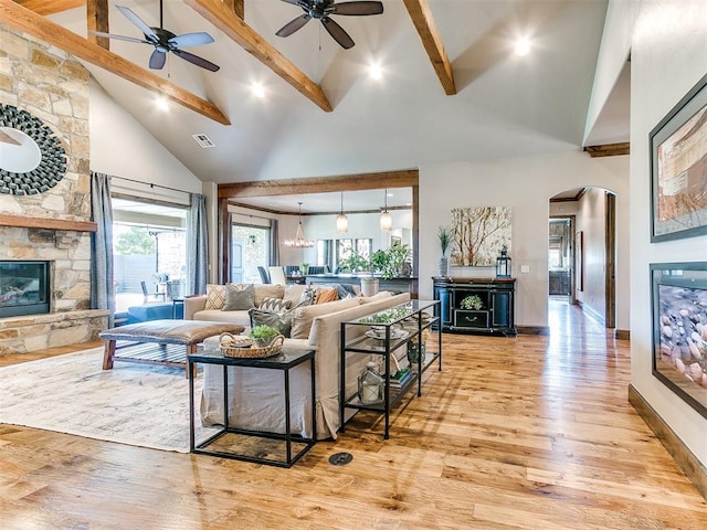 living room with a fireplace, beamed ceiling, high vaulted ceiling, and light hardwood / wood-style flooring