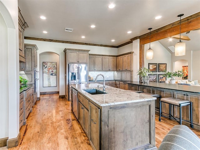 1205 Cobblestone Ln, Kingfisher, OK 73750 - kitchen featuring a sink, arched walkways, stainless steel appliances, light stone countertops, and hanging light fixtures