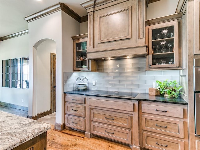 1205 Cobblestone Ln, Kingfisher, OK 73750 - kitchen featuring crown molding, arched walkways, black electric cooktop, decorative backsplash, and dark stone counters