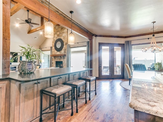 kitchen featuring hardwood / wood-style flooring, lofted ceiling with beams, a fireplace, and decorative light fixtures