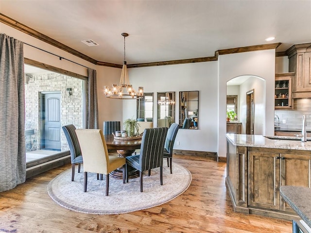 1205 Cobblestone Ln, Kingfisher, OK 73750 - dining space featuring a chandelier, arched walkways, ornamental molding, light wood-style floors, and baseboards