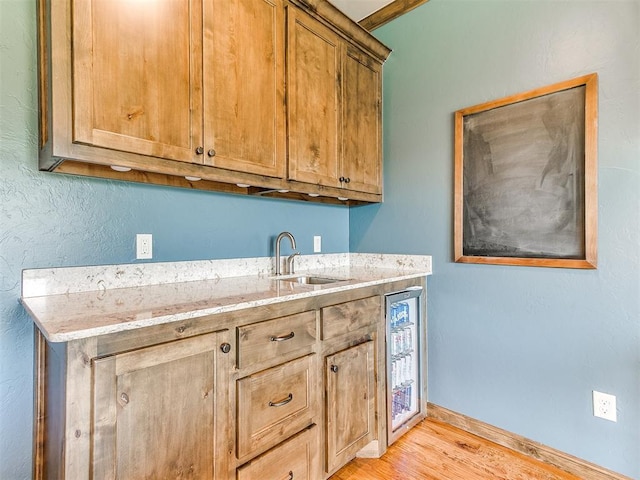 1205 Cobblestone Ln, Kingfisher, OK 73750 - kitchen with a sink, light wood-style flooring, baseboards, light stone countertops, and brown cabinets