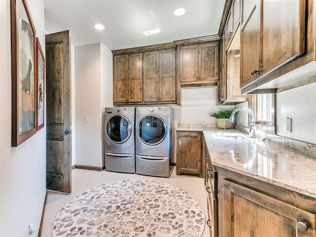 laundry room with washer and dryer, light tile patterned flooring, cabinets, and sink