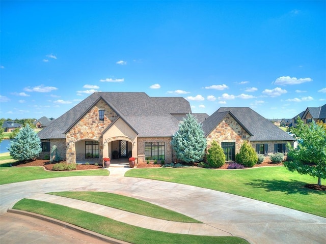 view of front of house featuring curved driveway, a front yard, and stone siding