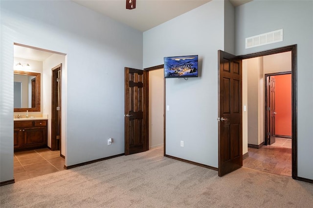 unfurnished bedroom featuring sink, light colored carpet, and ensuite bathroom