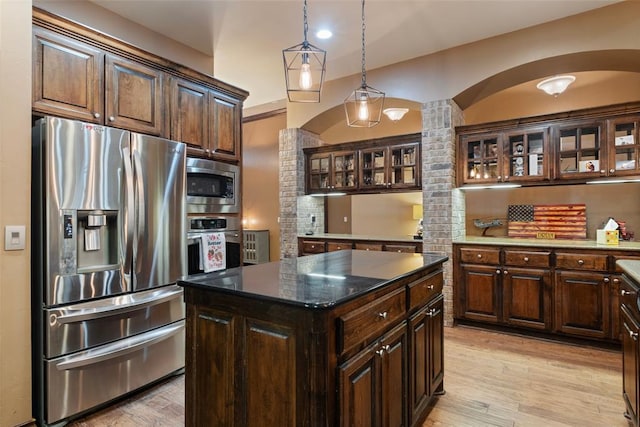 kitchen with appliances with stainless steel finishes, dark brown cabinetry, light hardwood / wood-style floors, and a kitchen island