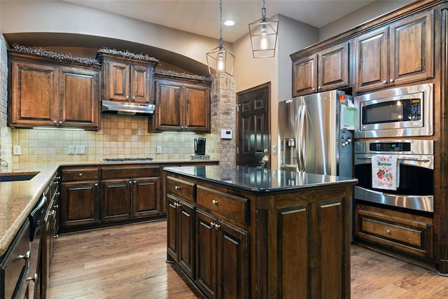 kitchen featuring hanging light fixtures, stainless steel appliances, tasteful backsplash, light hardwood / wood-style floors, and a kitchen island