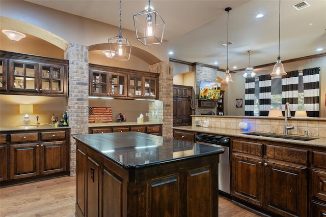 kitchen featuring decorative light fixtures, stainless steel dishwasher, a kitchen island, and sink