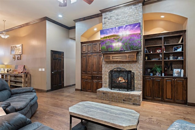 living room featuring a fireplace, light hardwood / wood-style floors, crown molding, and ceiling fan