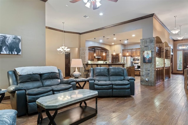 living room featuring hardwood / wood-style flooring, ceiling fan with notable chandelier, and ornamental molding