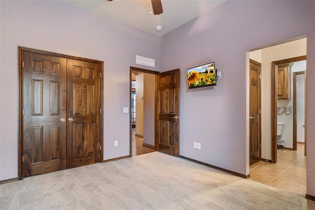 unfurnished bedroom with ensuite bath, light carpet, and ceiling fan