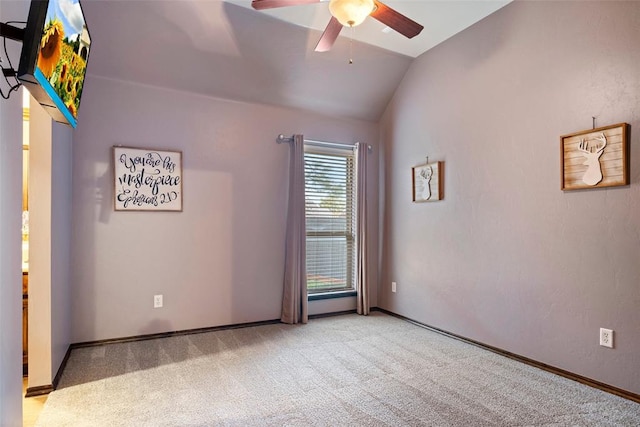 carpeted spare room featuring vaulted ceiling and ceiling fan