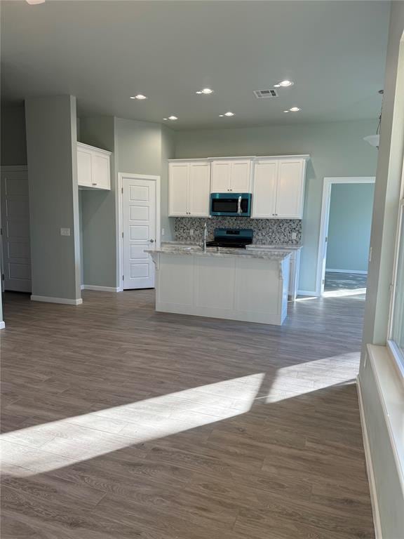 kitchen with tasteful backsplash, electric range oven, light stone countertops, and white cabinets