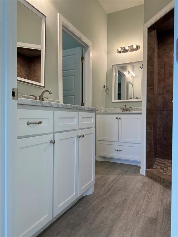 bathroom featuring vanity, hardwood / wood-style floors, and a tile shower