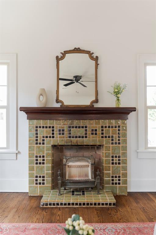 room details with hardwood / wood-style floors, ceiling fan, and a wood stove